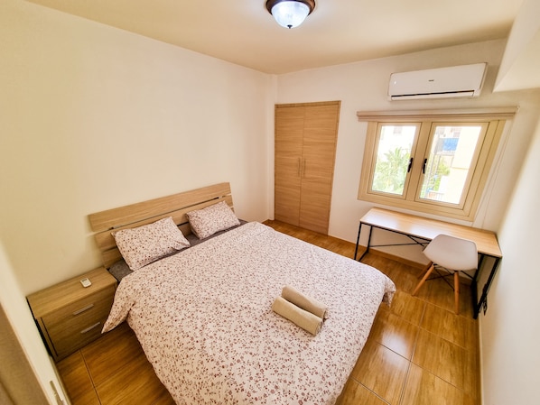 A bedroom with a bed, a desk, and a wardrobe.