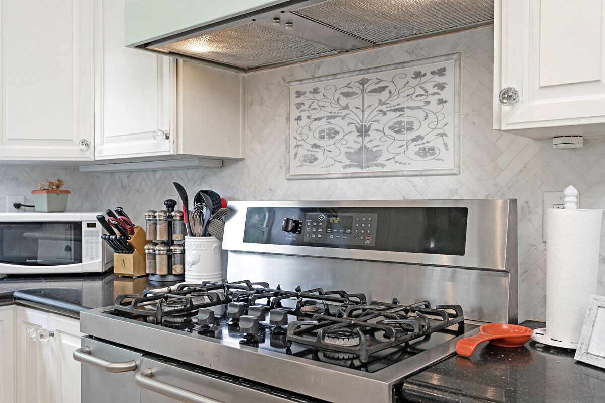 A kitchen with a gas stove, microwave, and stainless steel cabinets.
