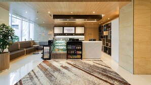 A modern hotel lobby with a reception desk, seating area, and a snack vending machine. - FOX Lite Hotel Grogol Jakarta (Jakarta)
