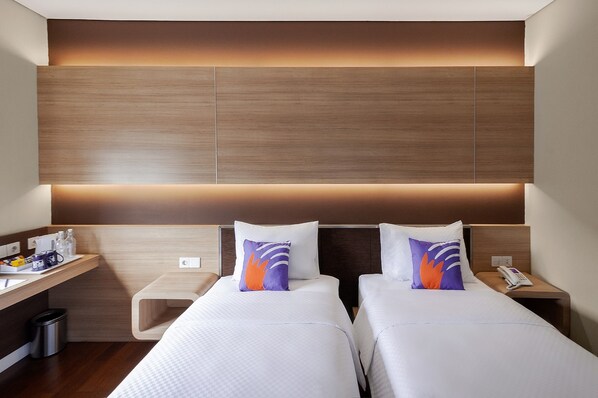 A hotel room with two beds, a desk with a chair, a nightstand with a phone, and a wall-mounted panel. - FOX Lite Hotel Grogol Jakarta (Jakarta)