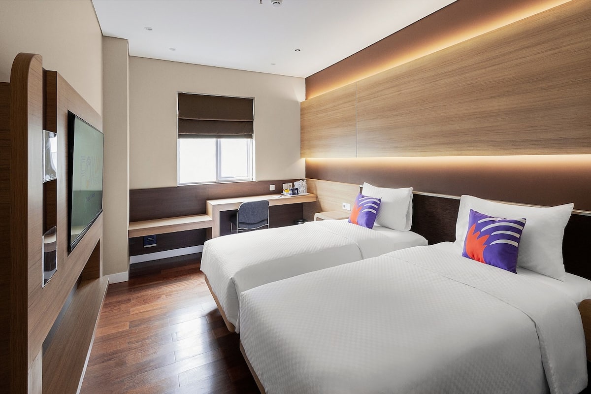 Une chambre d’hôtel avec deux lits, un bureau, une télévision et une fenêtre.