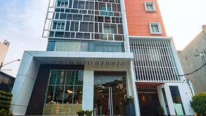 A modern building with a glass facade, a red accent wall, and a brick-paved entrance area. - FOX Lite Hotel Grogol Jakarta (Jakarta)