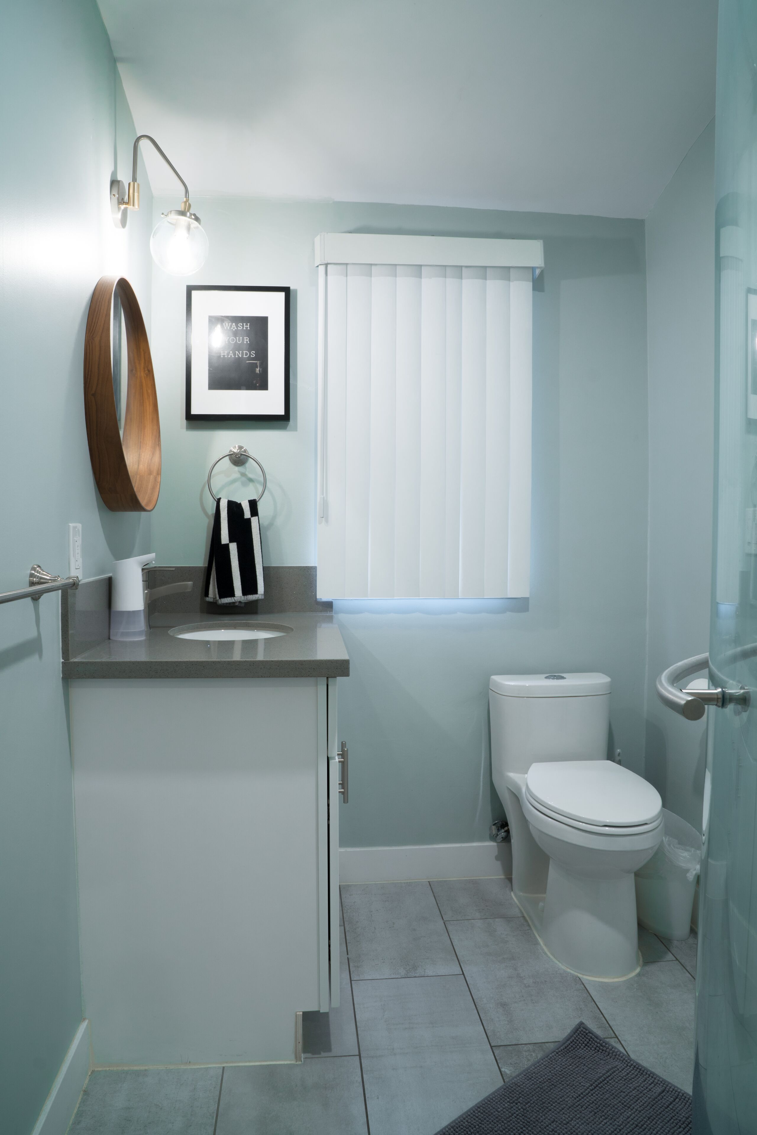 A bathroom with a toilet, sink, and mirror.