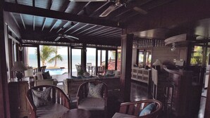 Un rincón tranquilo con muebles de madera, un bar y ventanas amplias con vistas al océano.