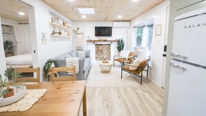 Una sala de estar acogedora con chimenea, muebles de madera y un televisor instalado en la pared.