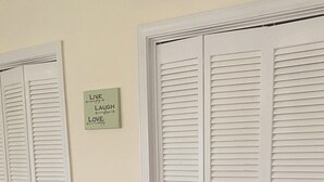Ein Flur mit drei weißen, durchgehenden Klappschranktüren und einem grünen Schild an der Wand.