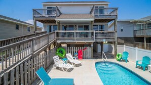 Une maison à deux étages avec un balcon, une piscine et un espace salon extérieur.