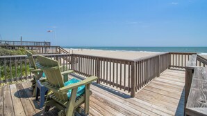 Une terrasse en bois offrant une vue sur la plage et l’océan.
