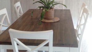 Un coin repas avec une table en bois, des chaises blanches et une plante en pot.