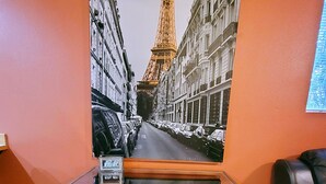 A room with a desk featuring a large painting of the Eiffel Tower, orange walls, and a leather chair. - Charming & Cozy Apartment w/ Hot tub patio. (Kenmore)