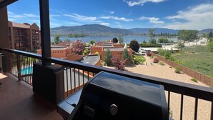 A balcony with a view of a lake, mountains, and a parking area. - Lakeshore Villas Resort - Three Bedroom Lakefront Condo  (Osoyoos)