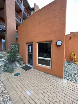 A modern building with a textured orange facade, a small entrance with a door, and a window. - Lakeshore Villas Resort - Three Bedroom Lakefront Condo  (Osoyoos)