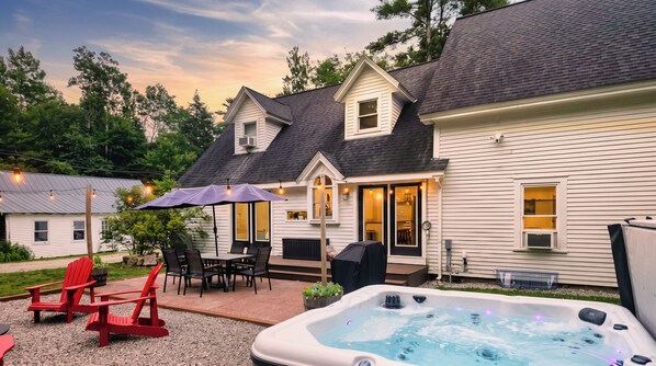 A house with a patio, outdoor seating, and a hot tub.