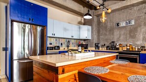 Une cuisine moderne dotée d’un îlot central, d’appareils électroménagers en acier inoxydable et de meubles de couleur bleue.