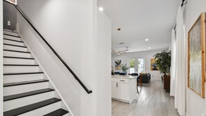 A modern interior with a staircase, a kitchen area, and a dining space.