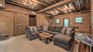 A cozy living room with a sectional sofa, a coffee table, and a wooden staircase. - The Edison - Hot Tub | Shuffleboard | Arcade Game | Firepit (Blue Ridge)