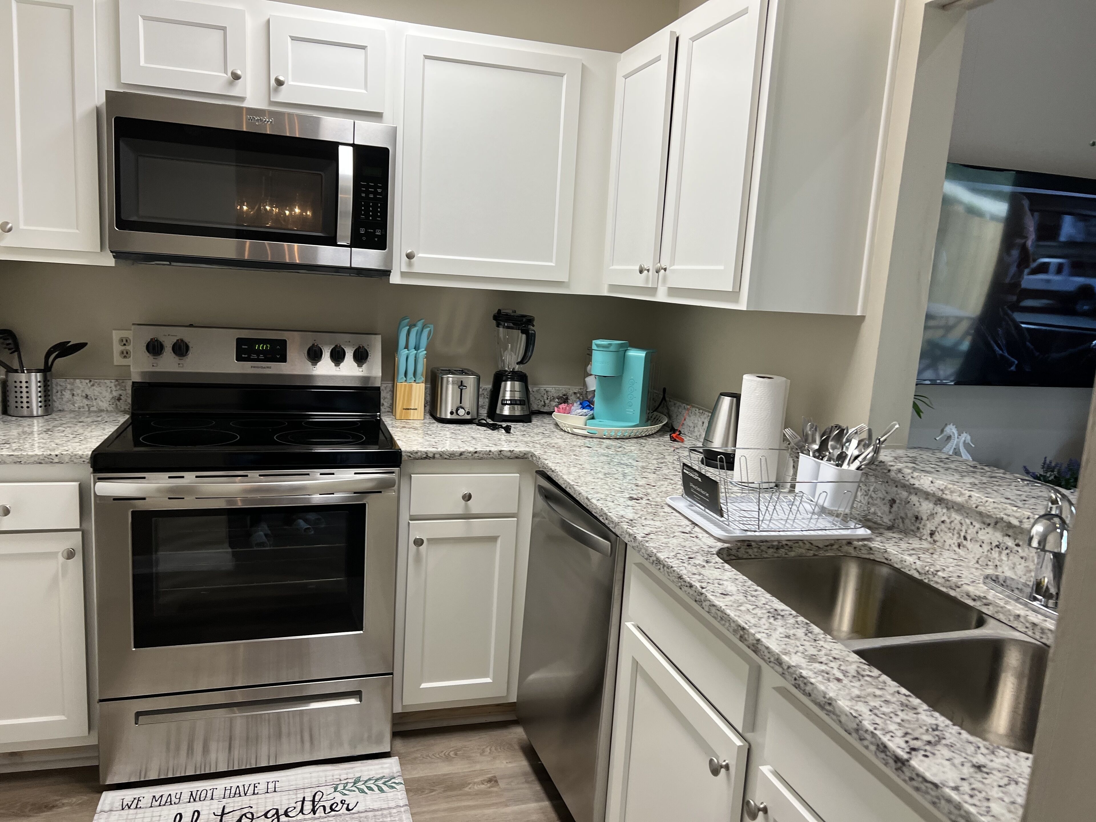 A modern kitchen with white cabinets, stainless steel appliances, and a granite countertop.