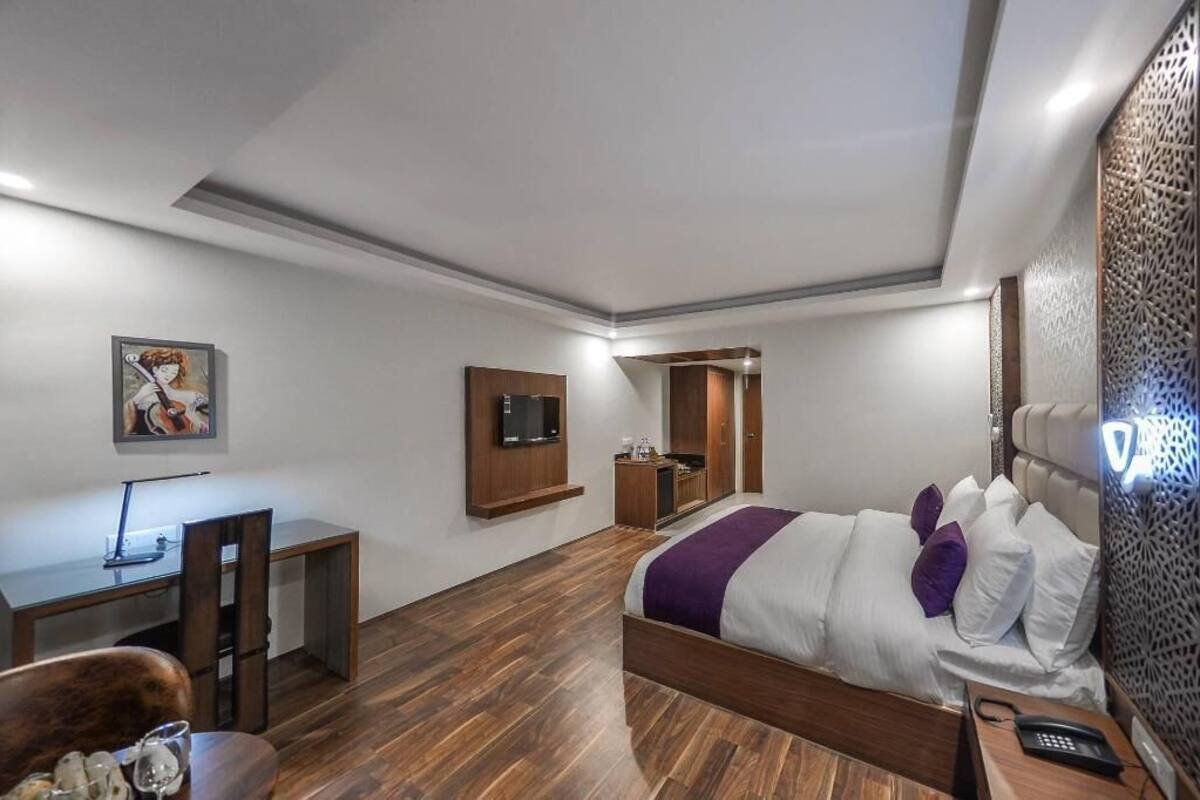 Una habitación de hotel moderna con cama, escritorio y televisor.