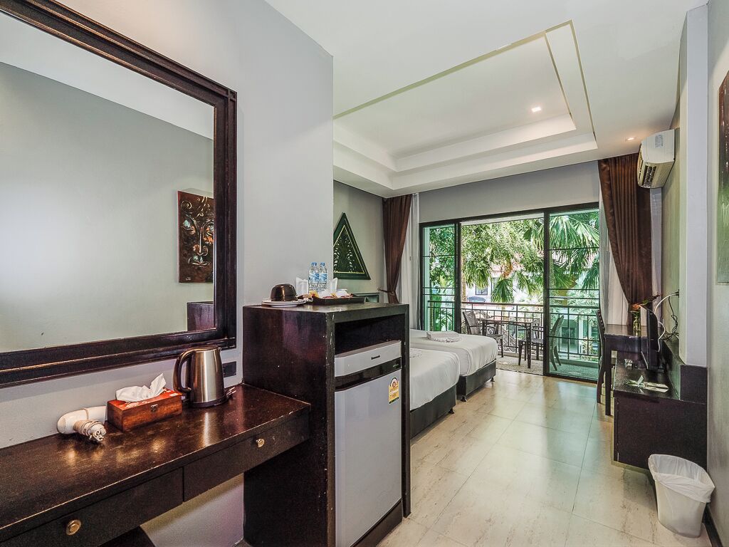 Habitación de hotel con cama, escritorio con cafetera, cesto de basura y vista al exterior.