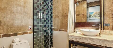 Un baño con ducha de vidrio, lavamanos blanco y un espejo grande.
