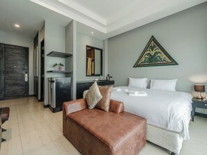 A hotel room with a bed, a brown leather sofa, a desk with a chair, a mirror, and a decorative wall piece.