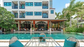 A hotel with a swimming pool, outdoor seating, and a covered area with tables and chairs. - Coco Paradiso Phuket Hotel (Chalong)