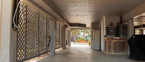 A covered outdoor area with a concrete floor, a grill, and a water heater.