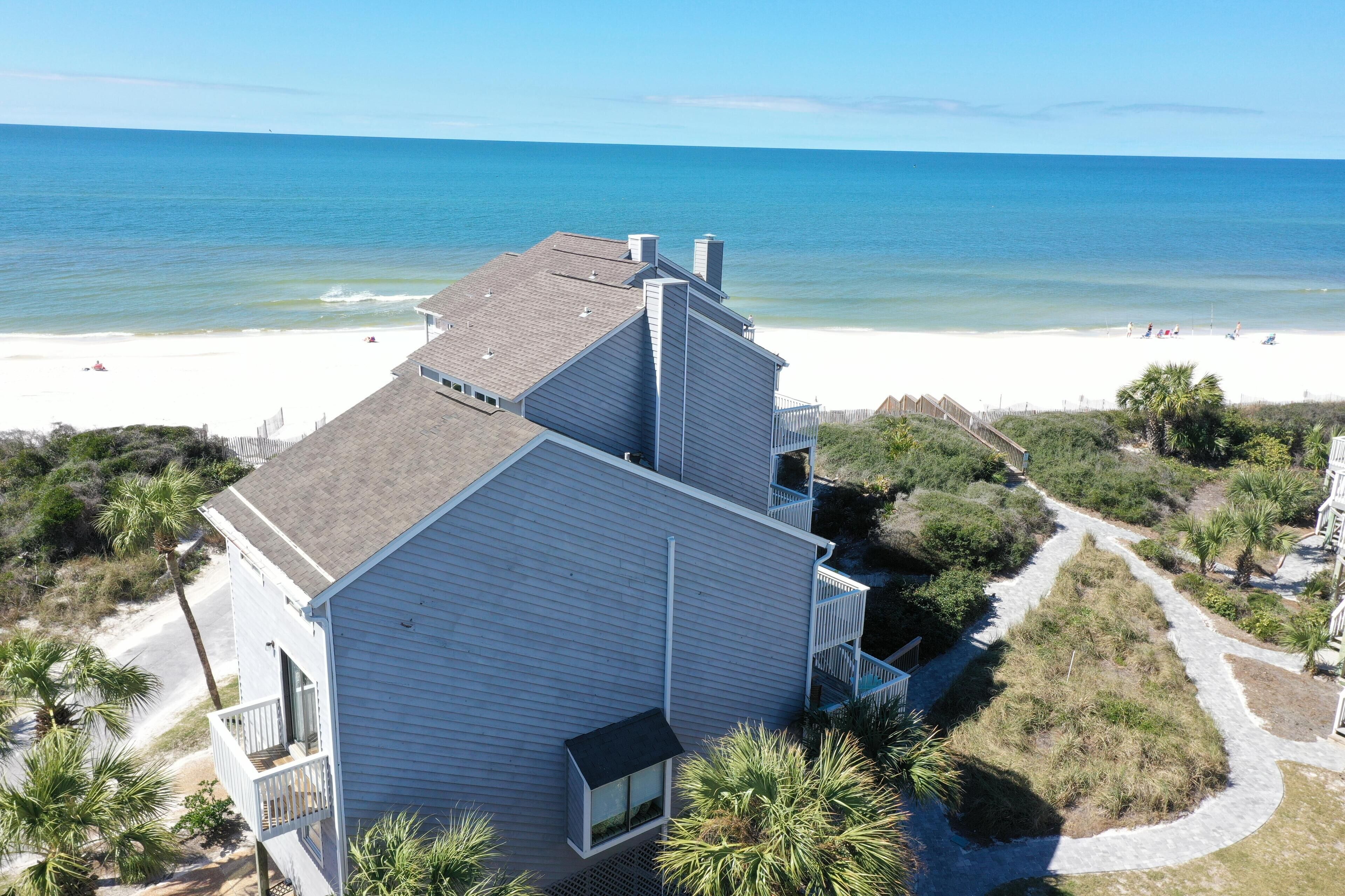 A beachfront property with a large building, a pathway, and a beach in the background.