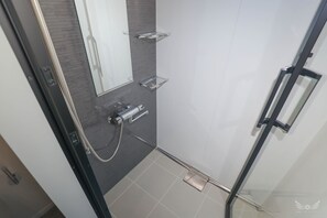 A modern bathroom with a glass shower enclosure, a built-in toilet, and a mirror. - FFFFFF HOTEL (Fukuoka)
