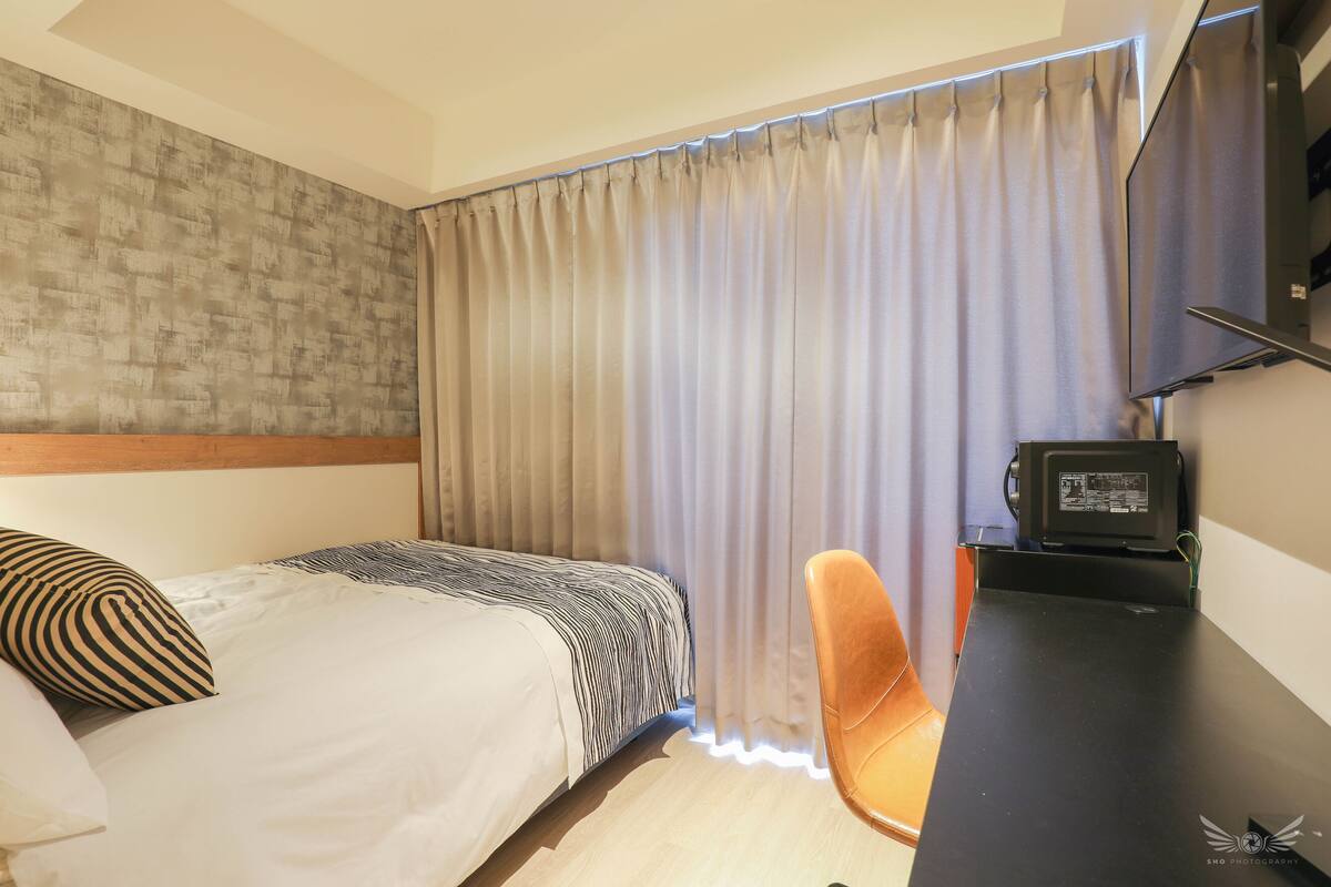 Hotellihuone, jossa on sänky, työpöytä ja tuoli.