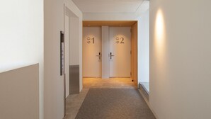 En gang med to døre mærket 81 og 82, et tæppe på gulvet og en loftlampe.