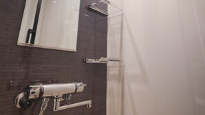 Et moderne badeværelse med stort spejl, bruseniche og håndklædetørrestativ.