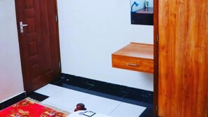 Ein Zimmer mit Holztür, einem Spiegel, einer kleinen Holzablage und einem Fliesenboden.