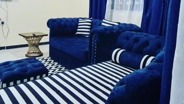 Ein Zimmer mit einem blauen Sofagarnitur, einem Streifen Teppich und einem kleinen Beistelltisch.