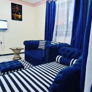 A room with a blue sofa set, a striped rug, and a small side table. - Stay.Plus Bamburi Mtambo Apartments (Mombasa)