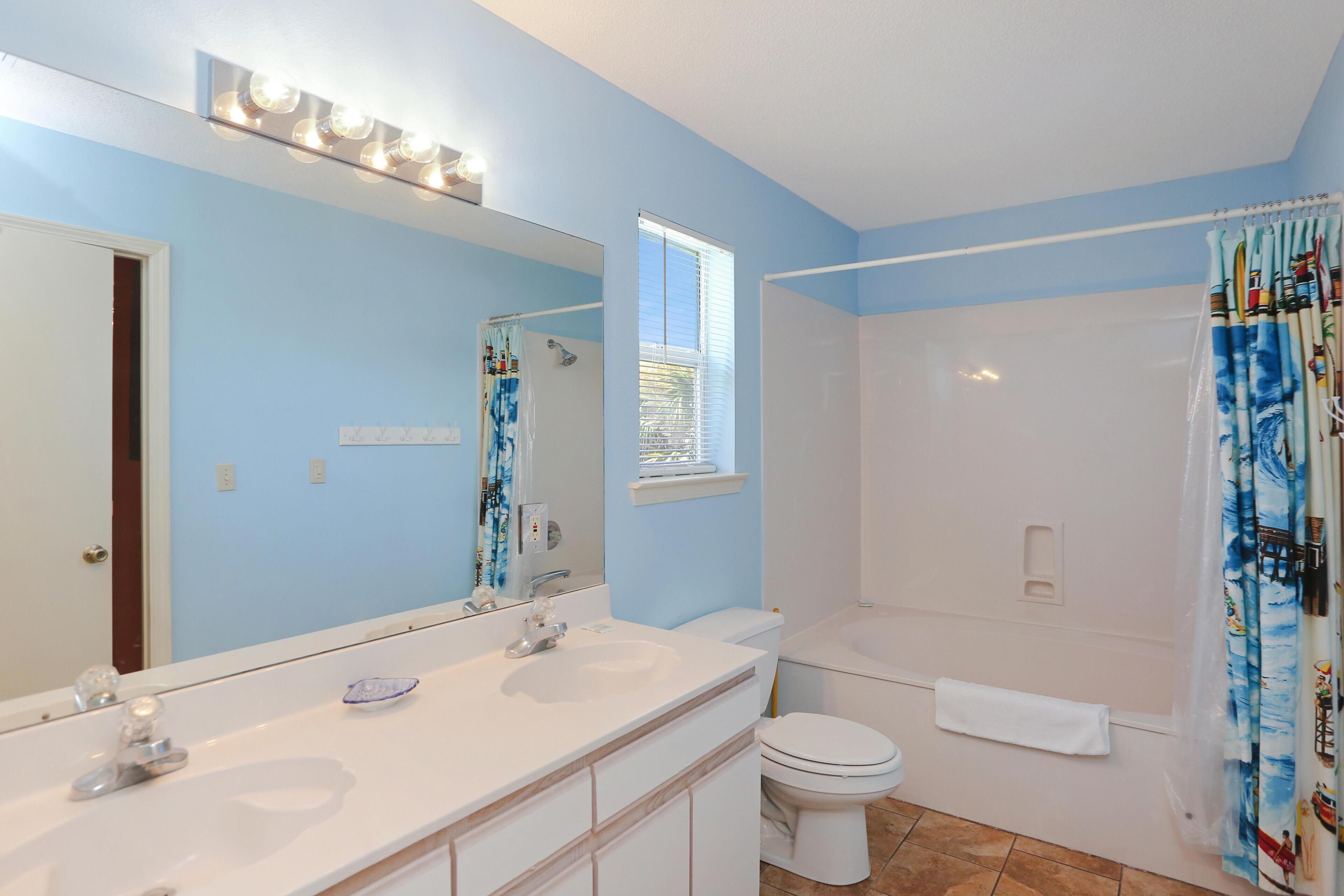 A bathroom with a double sink, a toilet, a shower, and a large mirror.