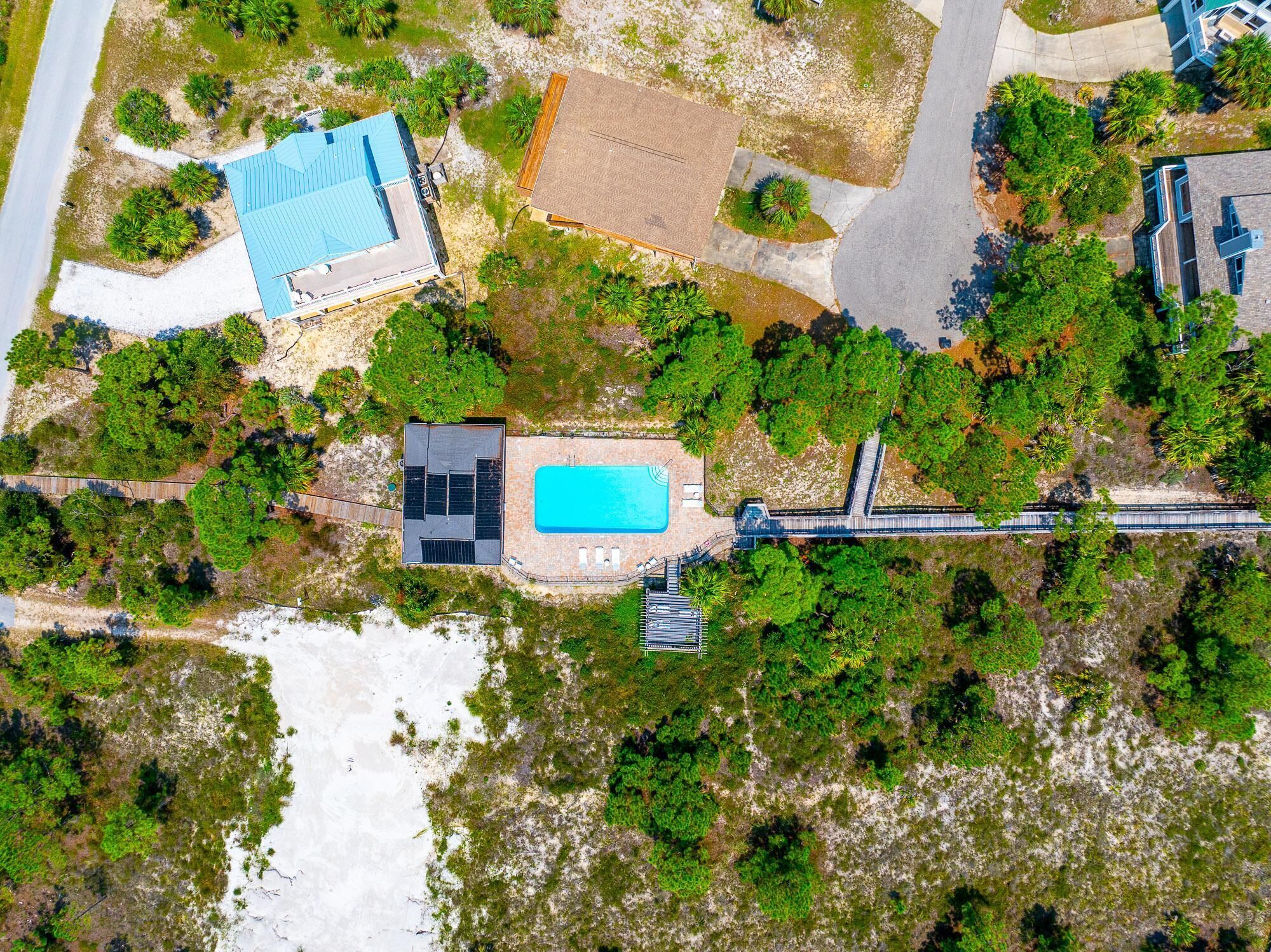 En vy från ovan av en fastighet med en swimmingpool, en täckt uteplats och ett stort öppet område.