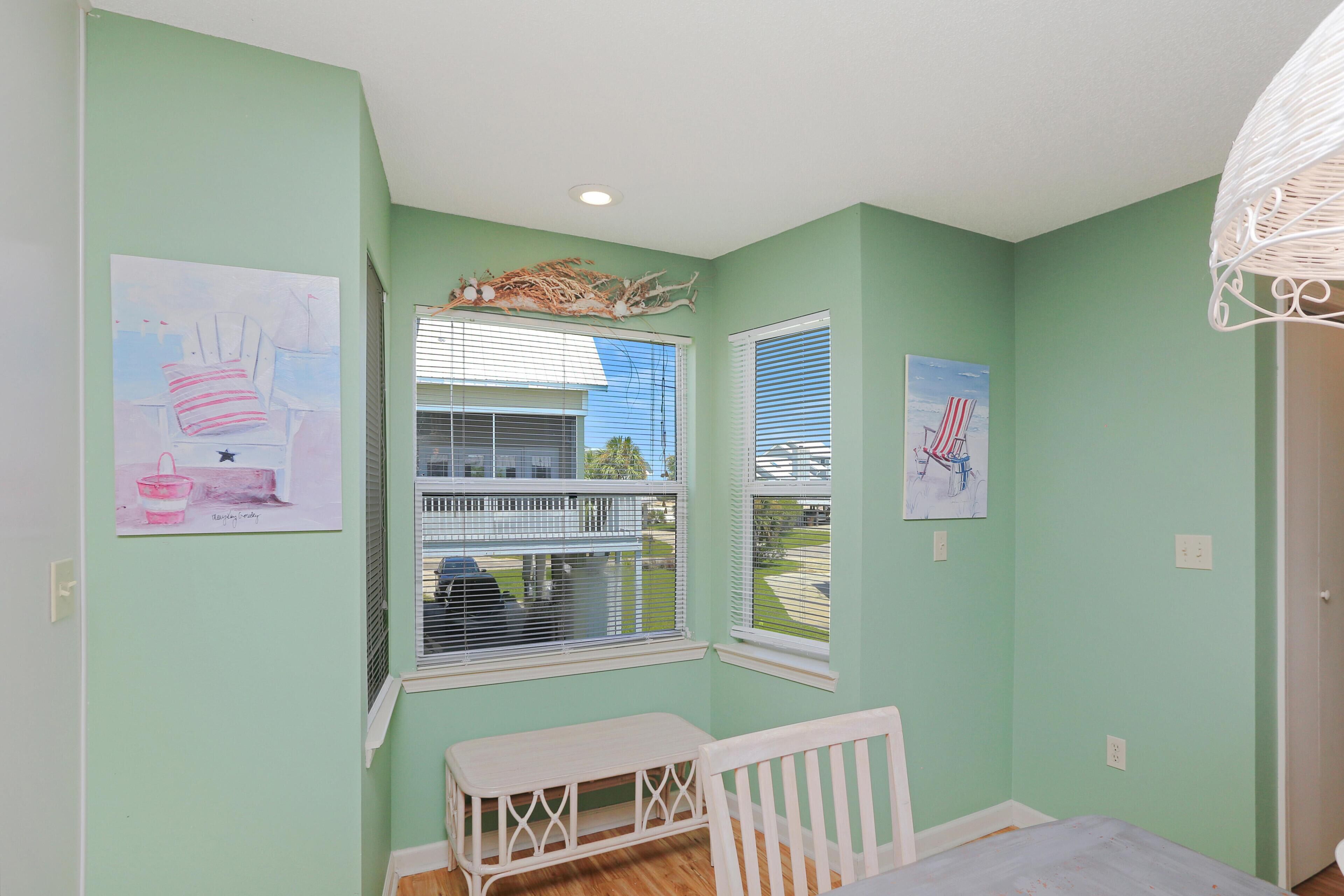 A room with light green walls, a white crib, and artwork on the walls.