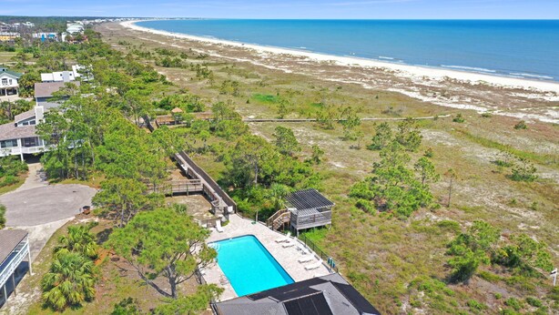 A residential property with a swimming pool, beachfront view, and a beach in the background. - Boardwalk Sandpiper (Port St. Joe)