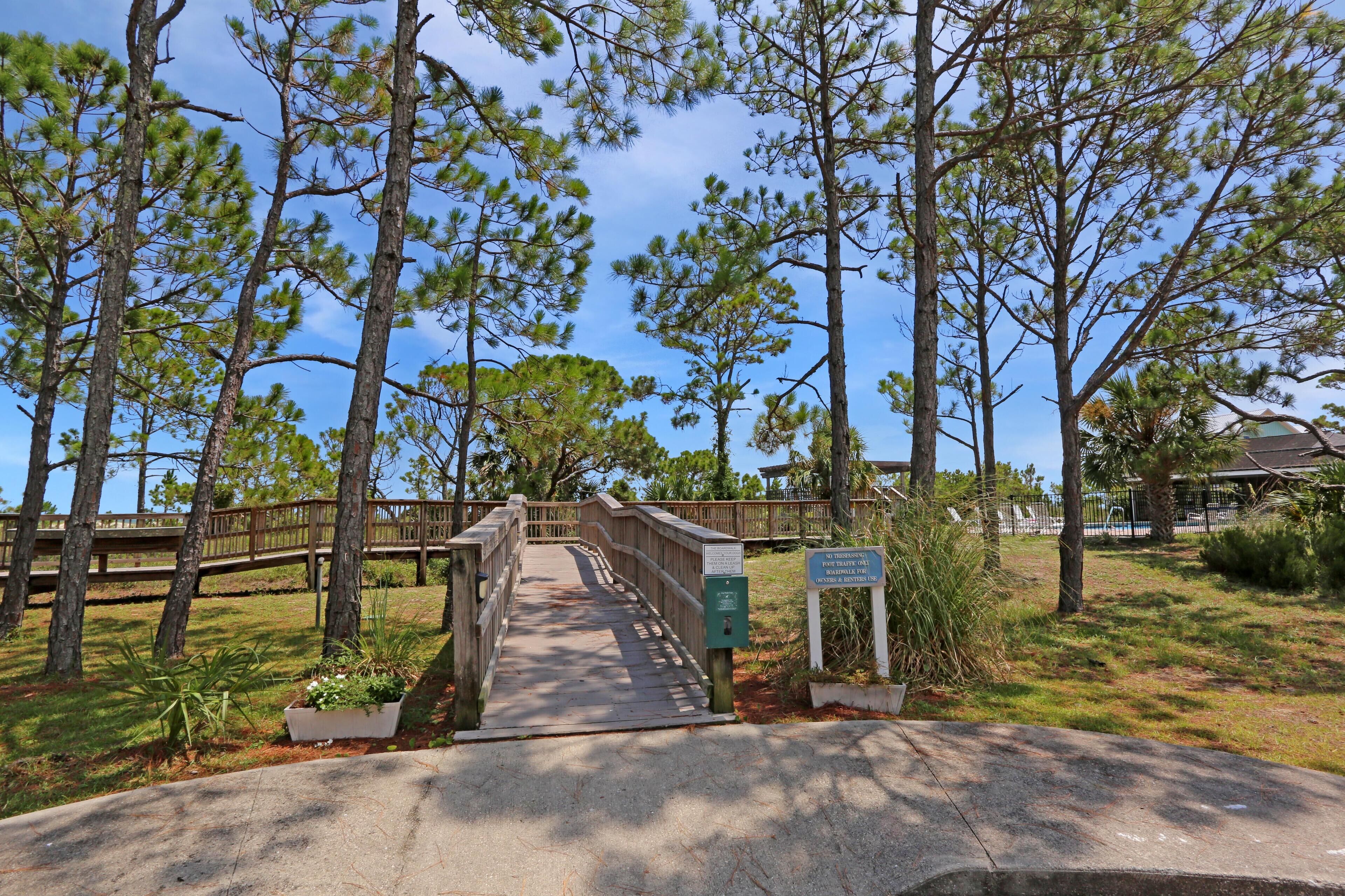 A wooden bridge leading to a building with a sign indicating a parking area.
