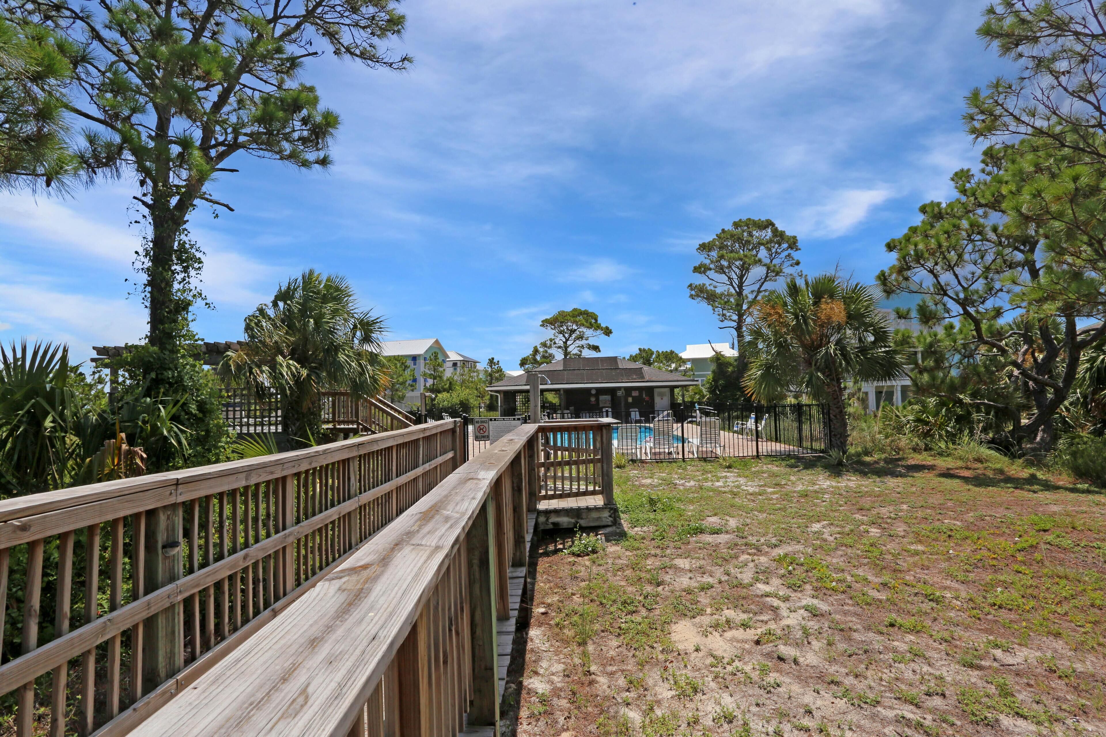 A wooden boardwalk leading to a building with a covered patio area.