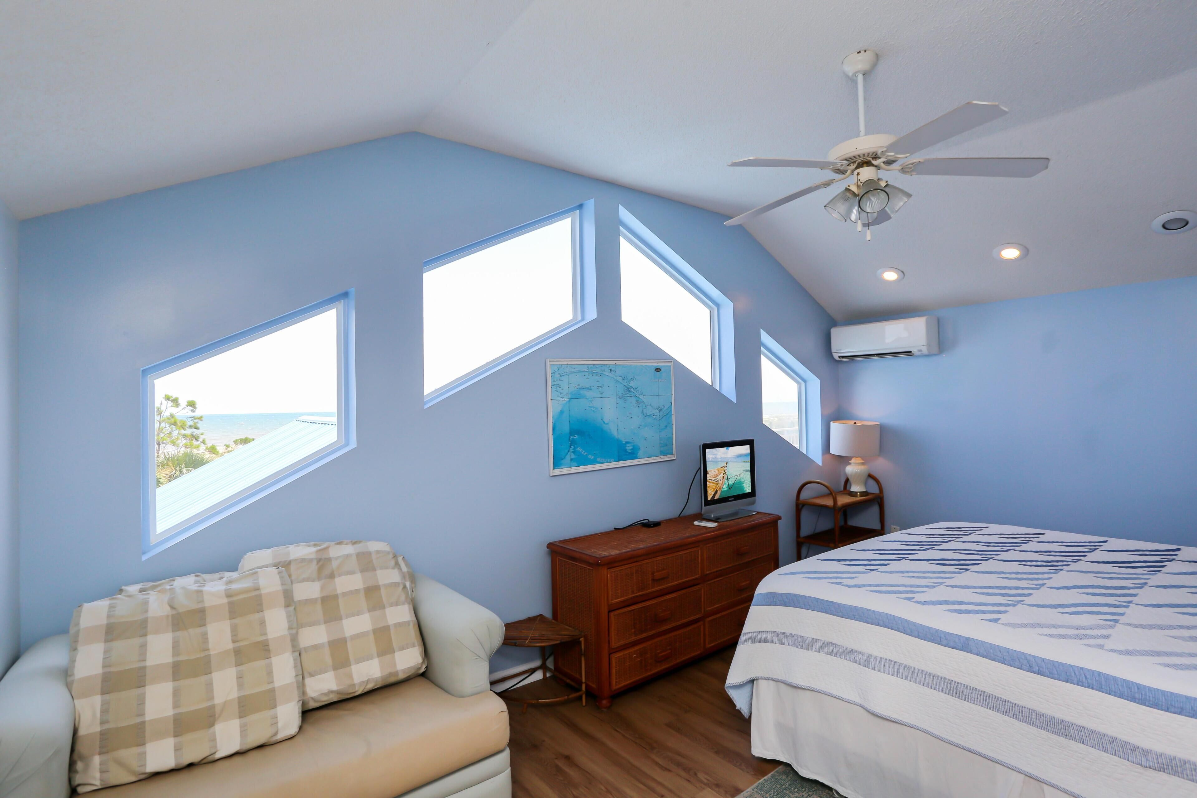 Un dormitorio con cama, tocador, silla, escritorio y ventana con vistas panorámicas.