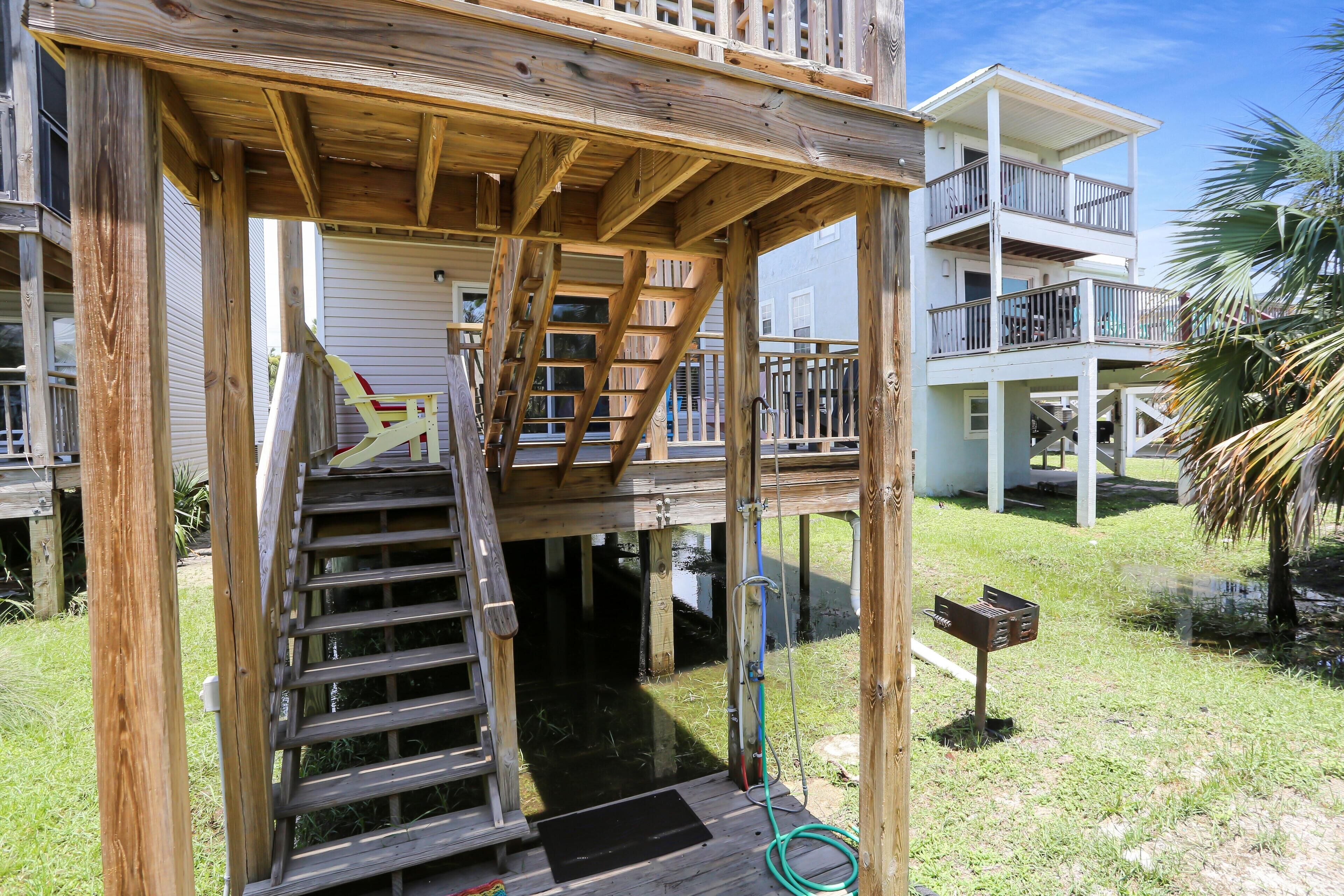 A wooden deck with a staircase leading to a second-story balcony.