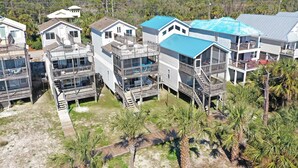 A beachfront property with multiple buildings, including a large house with a blue roof and a smaller house with a balcony.