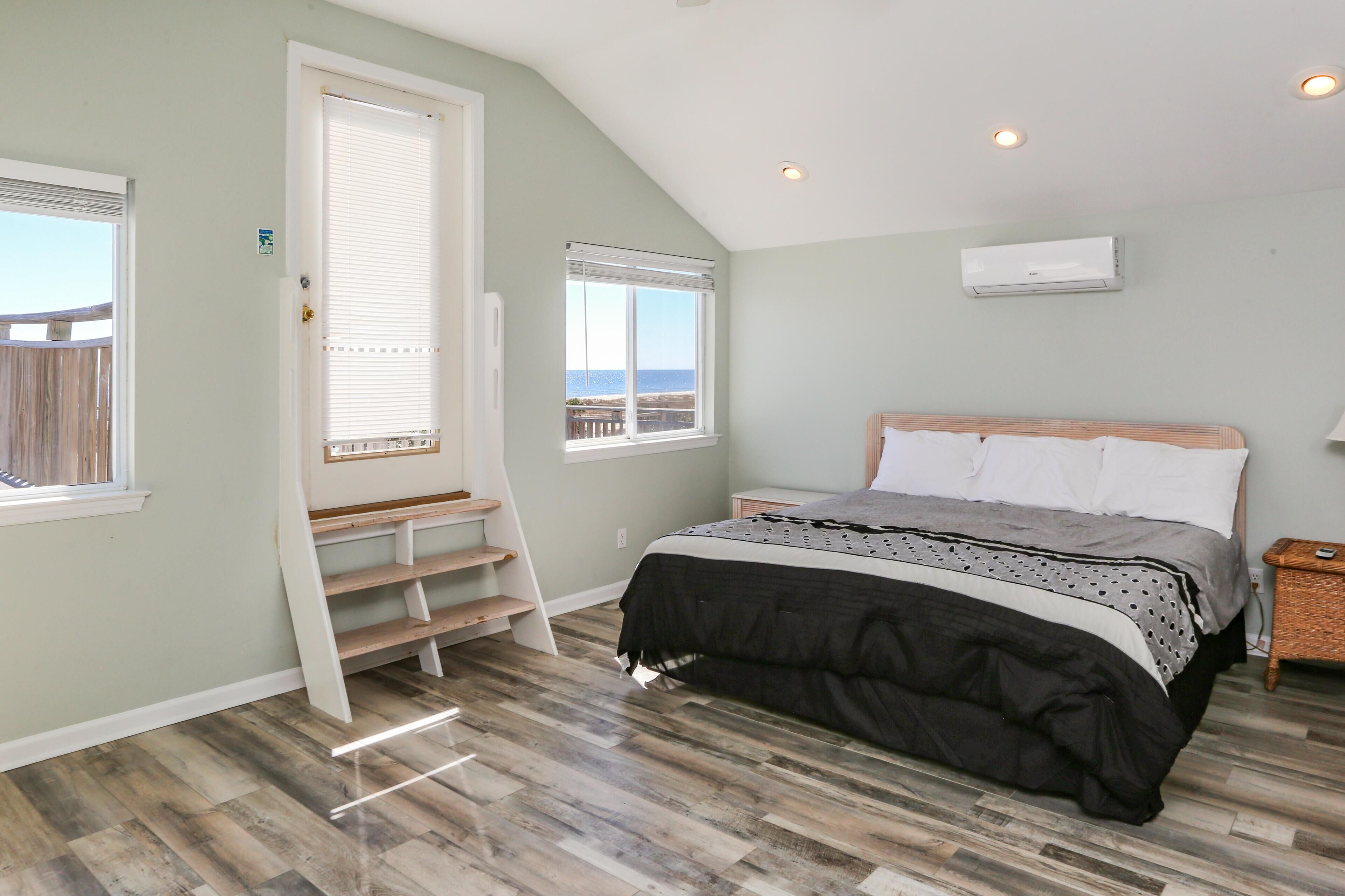 A bedroom with a bed, a window with a view, a built-in shelf, and an air conditioning unit.