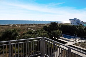 Une propriété située en bord de mer, dotée d’une terrasse en bois, d’une piscine et offrant une vue sur l’océan.