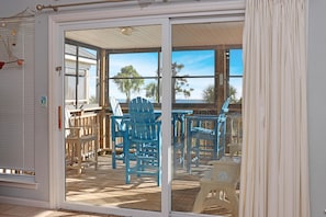 A room with a sliding glass door leading to an outdoor deck with blue chairs and a table. - Gulfside GEM (Port St. Joe)