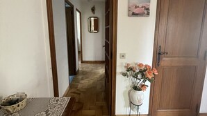 Un corridoio con una porta in legno, un vaso con fiori e un tavolo decorato.