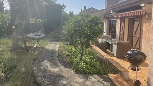 Un'area patio con una griglia, mobili da esterno e un vialetto che conduce a una casa.