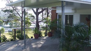 A covered outdoor area with a metal railing, potted plants, and a view of a residential neighborhood. - ~Exquisite Tiny House/Studio with Charm,Equipped Kitchen,Charming Outdoor Deck  (Alexandra Headland)